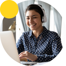 Happy woman with headphones on laptop wearing spotty shirt
